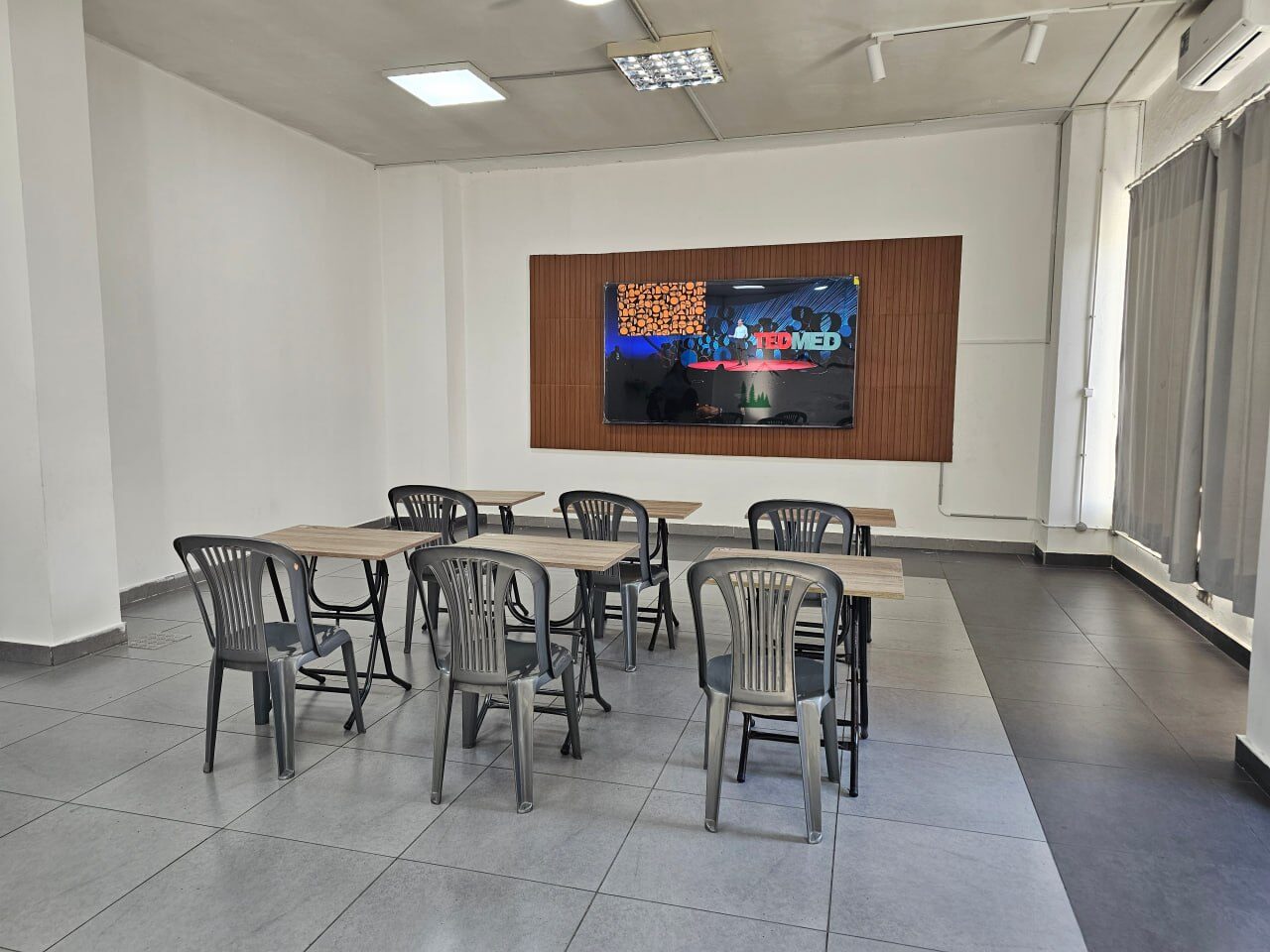 A classroom with desks, chairs and a big screen