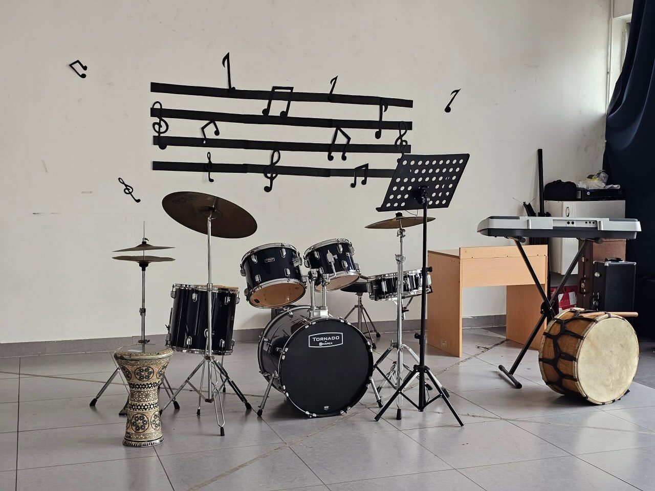 The music corner with a drum kit, a keyboard and music notes painted on the wall