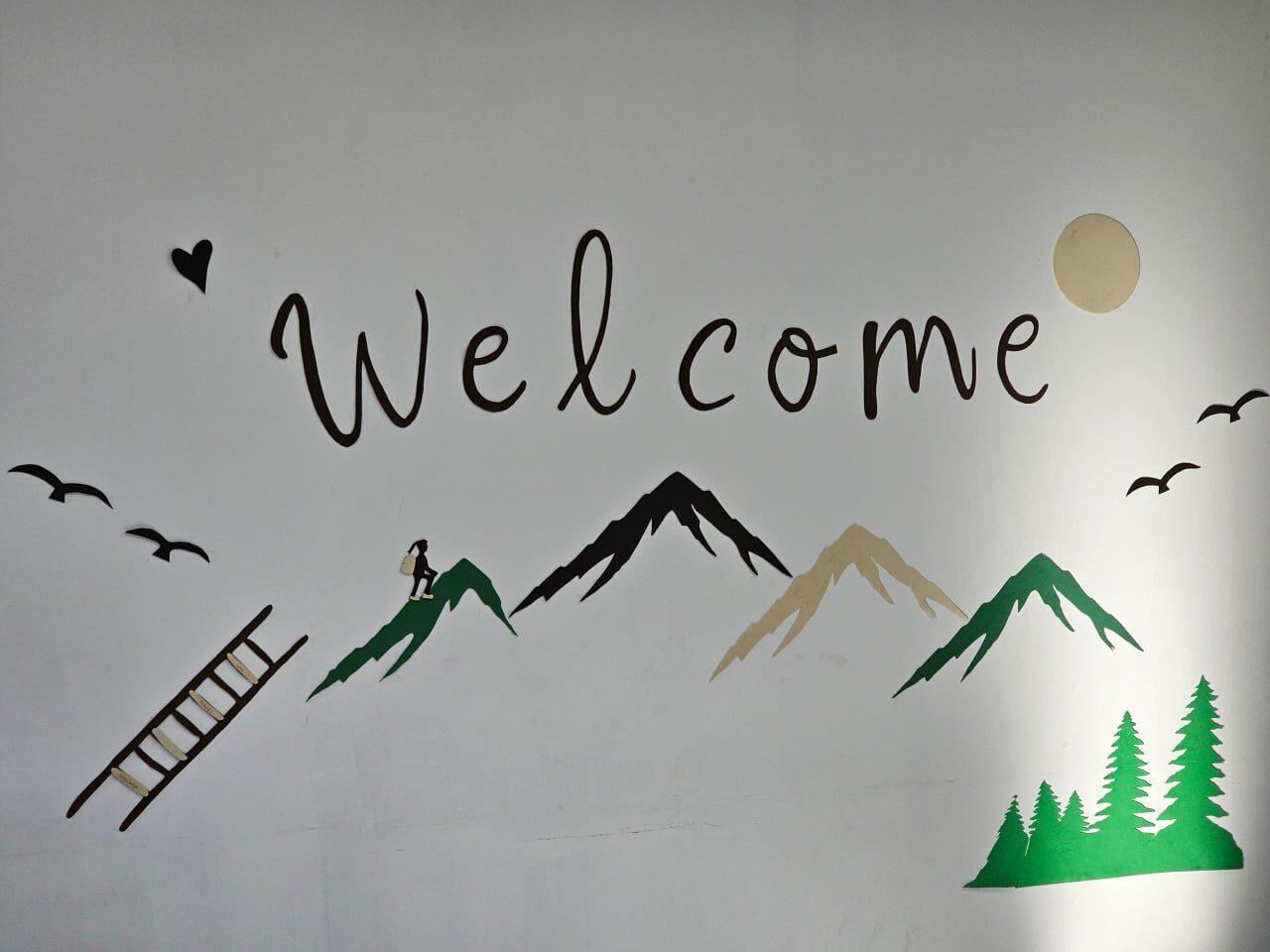 A painted Welcome mural with mountains, a ladder and birds